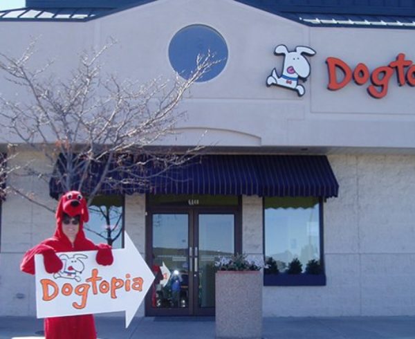 Dogtopia employee standing with advertisement sign for the company - a sign of high employee engagement through commitment.